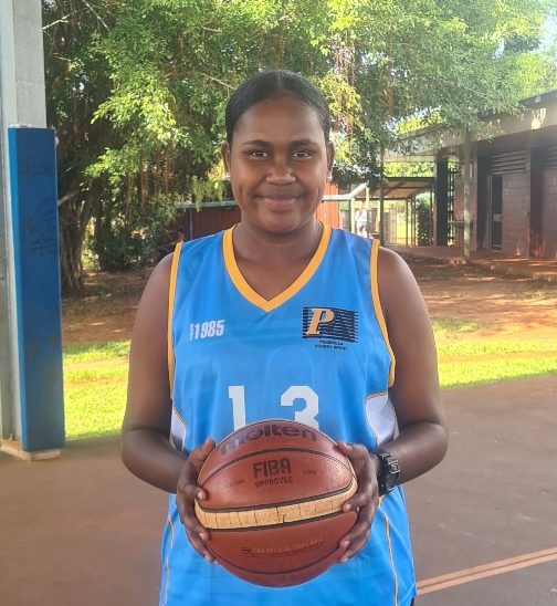 Young woman wearing a blue jersey holds basketball